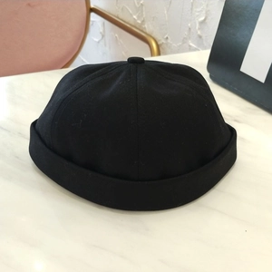 Gorro docker clásico de algodón negro sin ala sobre una elegante mesa de mármol
