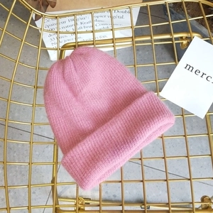 Close-up of pink angora wool beanie on gold chair showing detailed ribbed knit texture