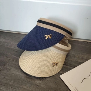 Women's straw open-top sun visor hat with golden bow accent in navy and beige