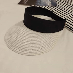 Detail of black and white straw visor hat with breathable mesh and refined woven texture