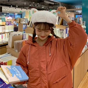 Close-up of white plush beret with cute teddy bear ears in a warm library setting