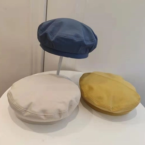 Minimalist solid color beret hats in navy, beige, and yellow with double stitching
