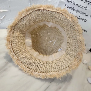 Detail showing inner woven sweatband and adjustable drawstring of straw hat with frayed edges