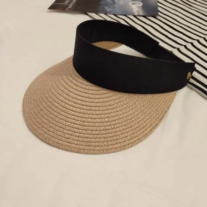 Detail of straw woven brim sun visor with black headband and gold metal triangle