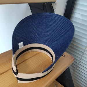 Detail shot of the 100% paper material label and navy blue woven brim on a sun visor hat