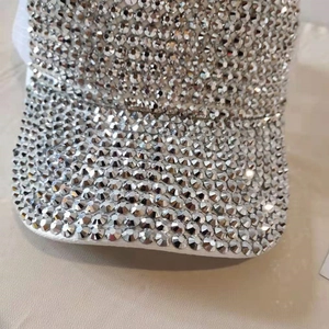 Close-up of sparkling silver rhinestones on the brim of a white baseball cap