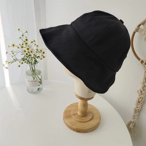 Close-up of black wide brim sun hat on a wooden mannequin stand in a minimalist room