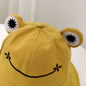 Detail eines gelben Frosch-Anglerhuts mit 3D-Augen und süßem Stickerei-Lächeln
