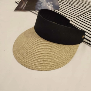 Detail of straw sun visor featuring a black band and a small gold metal triangle buckle