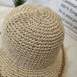 Detail of handwoven straw hat showing fine texture and frayed edges on natural fiber