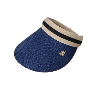 Deep blue straw sun visor with striped ribbon and gold bee accent on white background