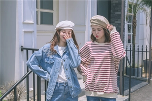 Detail of stylish beret hats worn with a denim jacket and striped sweatshirt for women