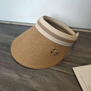 Close-up of woven straw visor texture featuring a beige ribbon and golden bow detail