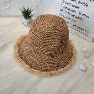Close-up of handmade straw bucket hat with frayed edges on a marble surface