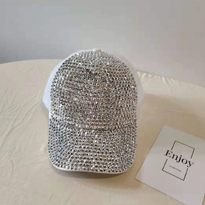 Close-up of sparkling silver rhinestones on the brim and crown of a white mesh trucker hat
