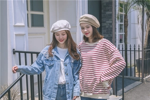 Detail of embroidered denim jacket and solid beret hats on models in street setting