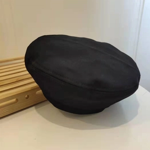Detailed top view of classic black beret hat with soft texture on white background