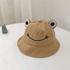 Nahaufnahme eines khakifarbenen Anglerhuts mit Froschaugen und gesticktem Smiley-Gesicht