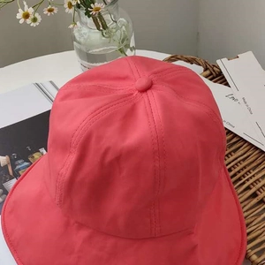 Close-up of pink foldable sun hat with fine stitching and top button on a woven basket