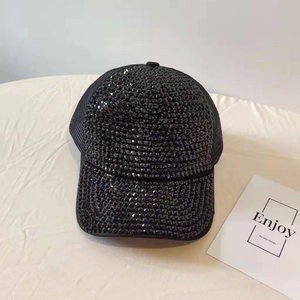 Close-up of black mesh trucker hat featuring shiny rhinestones and sequins on the brim
