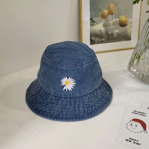 Detail van wit madeliefje borduursel op een blauwe denim bucket hat met casual decoratie