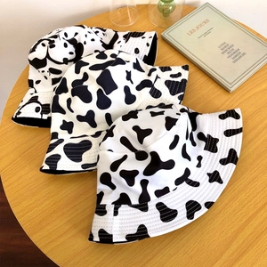 Trois bobs pour femmes au motif de vache sur une table en bois avec décorations