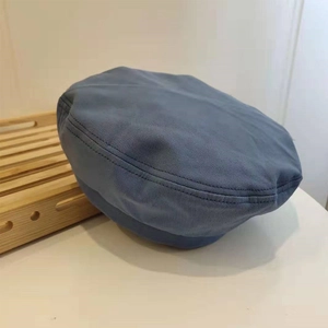 Detail view of the gray-blue vintage beret hat in twill cotton on a wooden tray