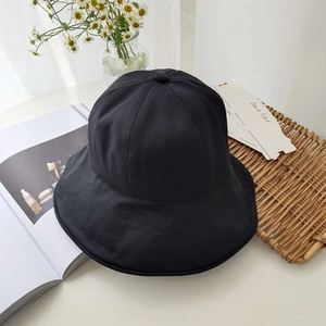 Flat lay of a stylish black foldable wide brim sun hat with daisy decor on a white table