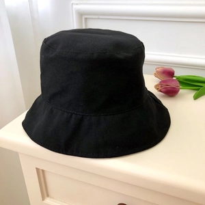 Close-up of minimalist black cotton bucket hat texture on a white decorative surface