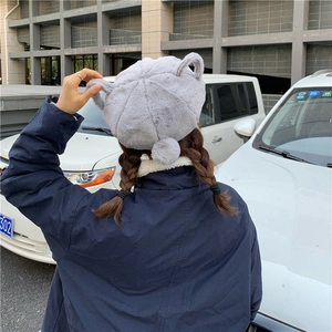 Detail view of the plush grey bunny ear beret with a fluffy pom-pom for winter wear