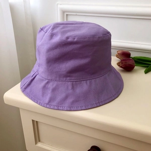 Detailed top view of a purple cotton bucket hat with fine stitching on cream cabinet