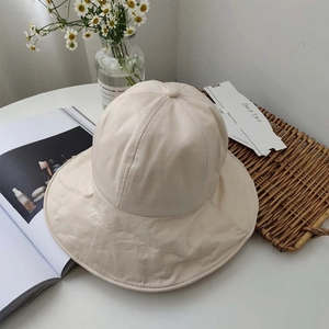 Overhead view of a foldable beige sun hat on a table with lifestyle decorative props