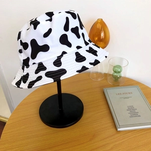 Détail du chapeau bob en toile imprimé vache exposé sur un porte-chapeau noir chic