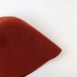 Detailed close-up showing the thick knitted texture and clay-red wool fabric of this bucket hat