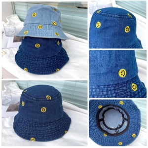 Detail of yellow smiley face embroidery on blue denim bucket hat with washing texture