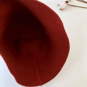 Detailed interior view of the rust red wool knit bucket hat showing fine stitching