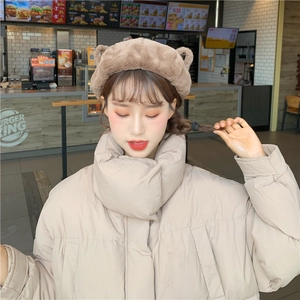 Close-up of fluffy brown bear ear beret paired with a beige winter puffer jacket