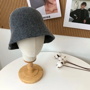 Detailed texture of grey wool felt bucket hat on a wooden mannequin head stand
