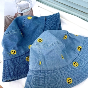 Close-up of denim bucket hats with yellow smiley face embroidery and neat stitching