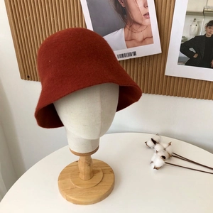 Detail of terracotta wool bucket hat with knitted texture on a minimalist display stand