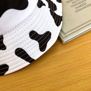 Vue détaillée du tissu en coton à motif vache et des coutures de ce chapeau bob