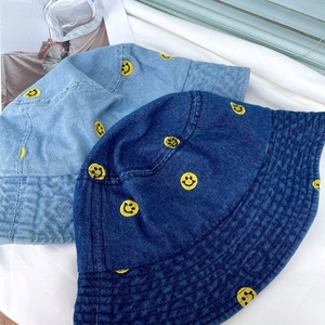 Detailed embroidery of yellow smiley faces on light and dark blue denim bucket hats