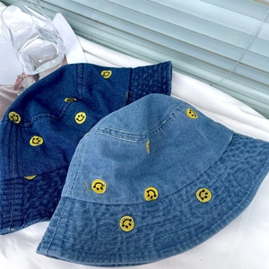 Detail of denim bucket hats with yellow smile embroidery and vintage texture