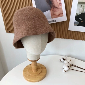 Detail of warm brown wool bucket hat showing soft knitted texture on display stand