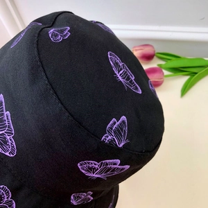 Close-up of black cotton bucket hat featuring detailed purple butterfly print patterns