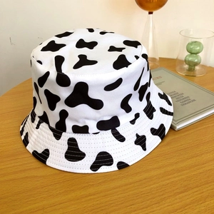 Détail d'un chapeau bob tendance à motif vache noir et blanc sur une table en bois