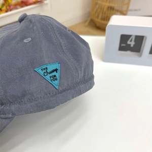Close-up of grey vintage baseball cap with a blue triangle patch and cotton texture