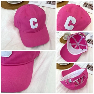 Detail view of pink cotton baseball cap with embroidered letter C and adjustable metal buckle
