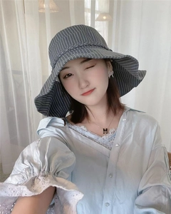 Detail of grey striped sun hat featuring a wide wavy brim and woven decorative band