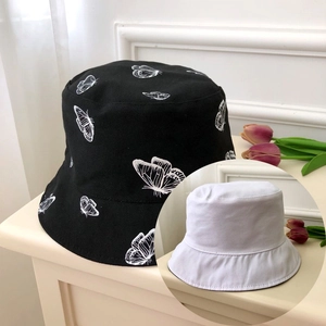 Detail of black bucket hat with white butterfly prints and a solid white reversible side